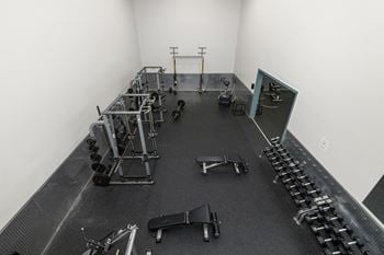 A gym with weights and cardio equipment in a white room